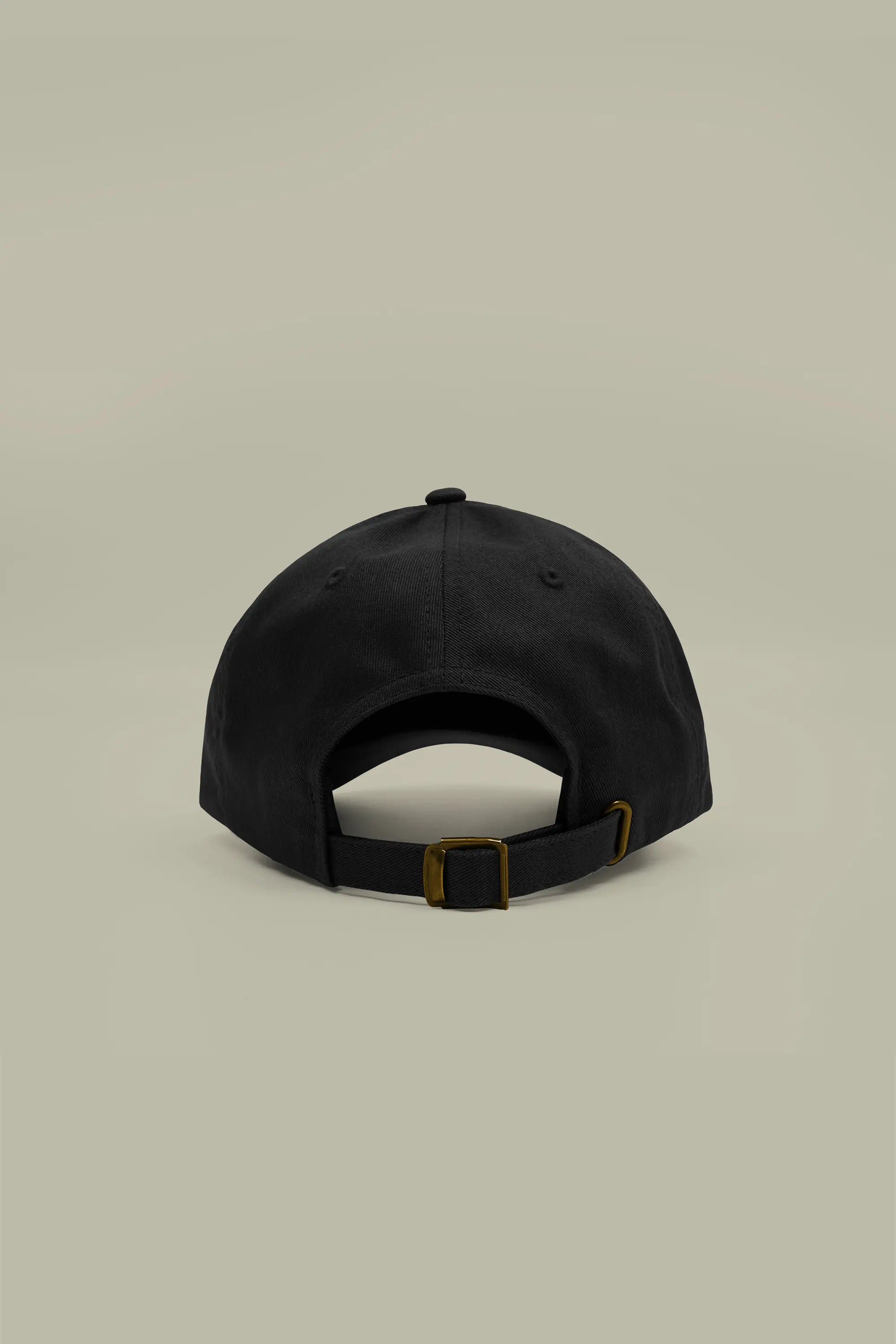 Black cap with a gold buckle on a beige background