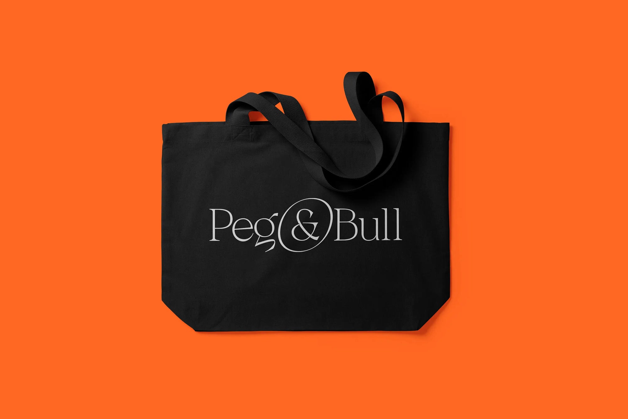Black tote bag with 'Peg & Bull' logo on an orange background