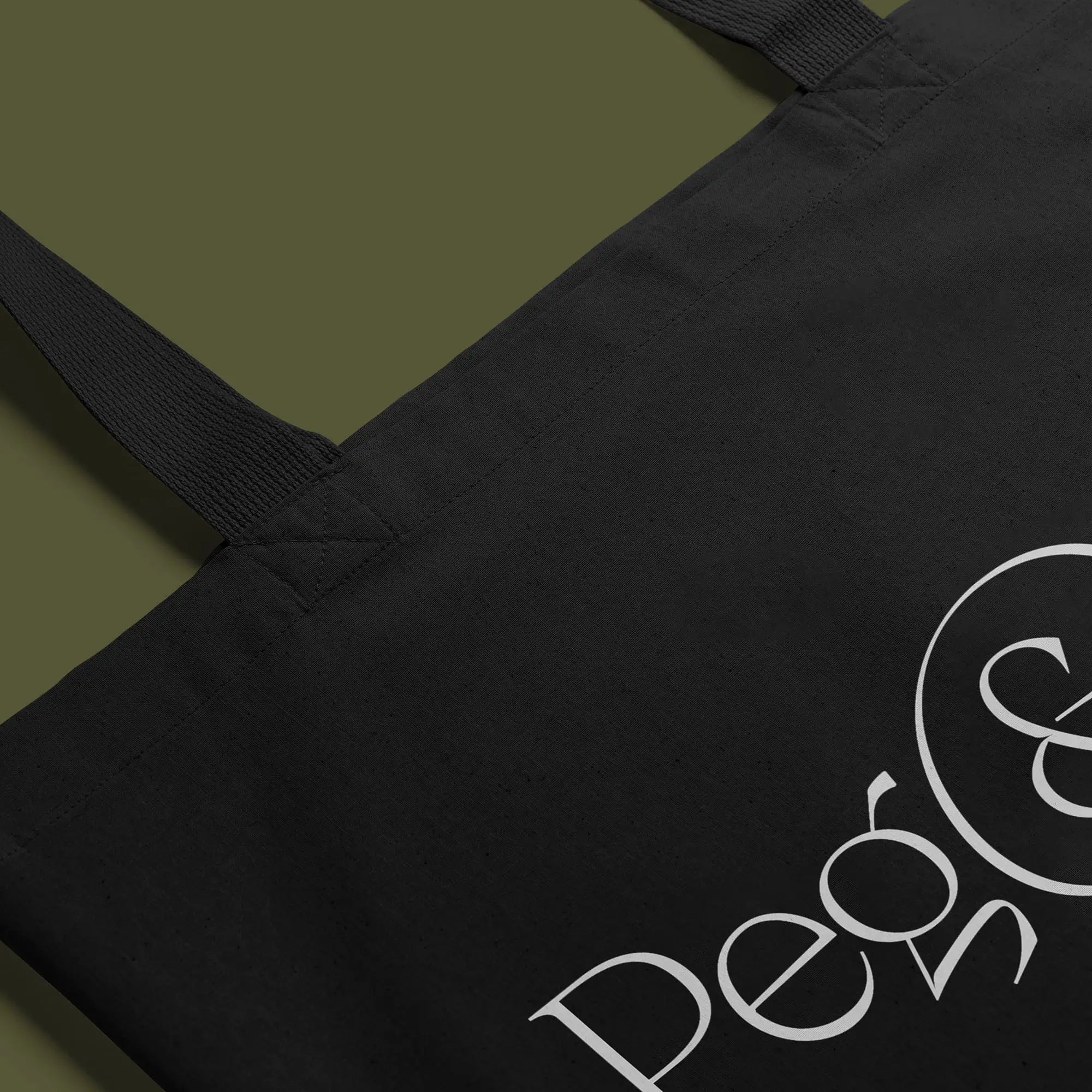Black tote bag with white Peg & Bull logo on a green background