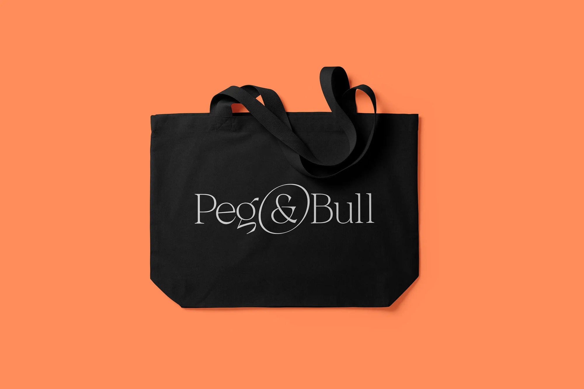 Black tote bag with 'Peg & Bull' logo on an orange background